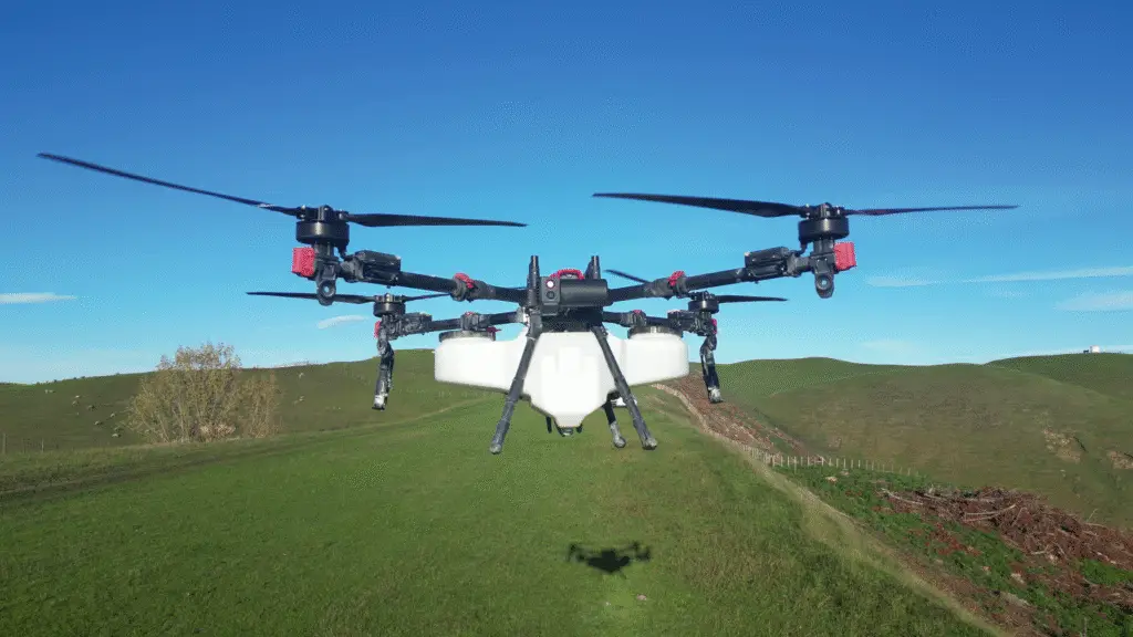 XAG P150 spray drone hovering over farmland hills in New Zealand.